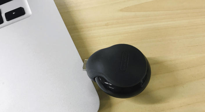 máy ảnh toàn cảnh Xiaomi MADV Mini bọc silicon màu đen, đặt cạnh laptop trắng